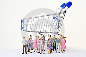 Miniature toy people stand near shopping cart