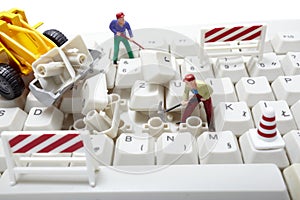 Miniature toy workers repairing computer keyboard photo