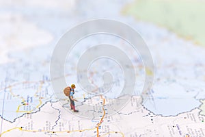 Miniature traveler with backpack standing on wold map for travel around the world. photo
