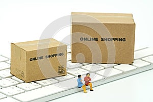 Miniature two people sitting on white keyboard Online shopping w