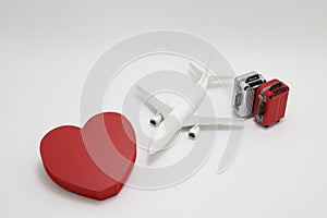 Miniature two suitcases, miniature toy airplane, and a red heart on white background.