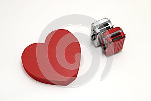 Miniature two suitcases and a red heart on white background.