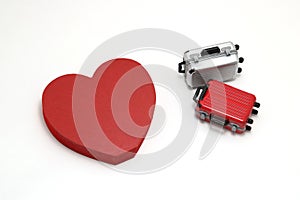 Miniature two suitcases and a red heart on white background.