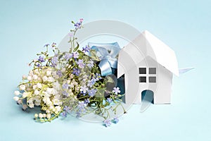 Miniature white toy house with bouquet of lily of the valley and forget-me-nots