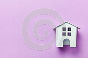 Miniature white toy house on purple violet pastel background