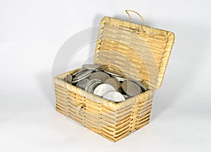 Miniature wicker chest filled with different coins on white background, saving money concept