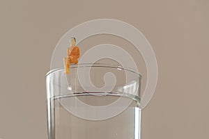 Miniature woman figure siting on the glass of water. Shallow depth of field background. Healthcare, healthy lifestyles and