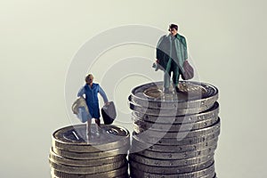 Miniature woman and man on piles of euro coins