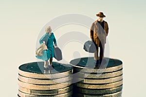 Miniature woman and man on two piles of coins