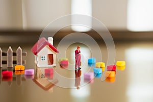 Miniature woman standing with mini house