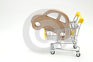 Miniature wooden car and shopping cart on white background. Concept of buying new car.