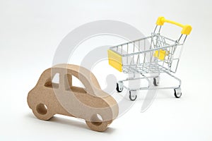 Miniature wooden car and shopping cart on white background. Concept of buying new car.