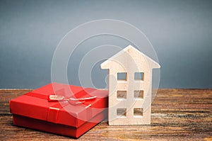 Miniature wooden house and gift box. The concept of profitable offers for the purchase of real estate. Inheritance of housing.