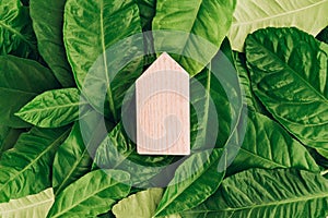 Miniature wooden house on green leaves. Eco-friendly and energy efficient house concept