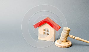 Miniature wooden house and judge`s hammer. The concept of resolving property disputes. Property alienation. Confiscated housing.