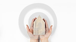 Miniature wooden house model. Home insurance and protection. Construction buying a home loan. In hand on a white background.