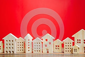 Miniature wooden houses on a red background. Real estate concept. City. Agglomeration and urbanization. Market Analytics. Demand