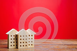 Miniature wooden houses on a red background. Real estate concept. City. Agglomeration and urbanization. Market Analytics. Demand photo