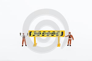 Miniature worker with work in progress sign isolate on white background