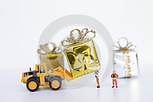 Miniature worker and yellow truck moving gift