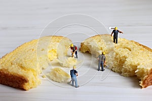 Miniature workers cutting bread.