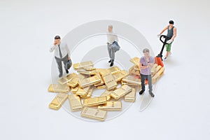 Miniature Workers Managing Stack Of Metallic Gold Bars