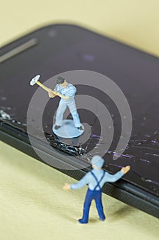 Miniature Workers recycling a broken cell phone