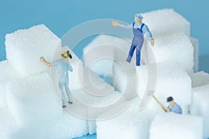 Miniature workers working between several cubes of sugar