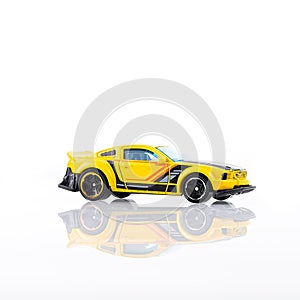 Miniature yellow car on white background and with reflection