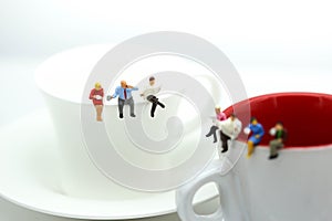 Miniatures people : sitting on a cup of coffee,relax and business concept.