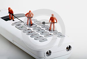 Miniatures of workers fixing a cordless phone