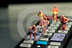 Miniatures of workers fixing a remote control