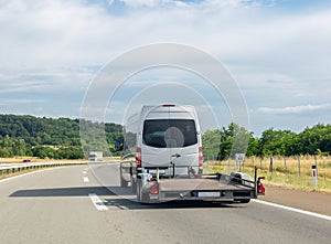 Minibus with empty tow truck transporter on highway. Space for text