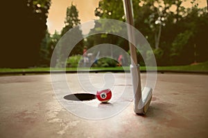 Minigolf player tries to put a small billard ball into the hole