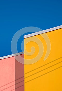 Minimal architecture background of colorful vintage building wall against blue clear sky in low angle view and vertical frame