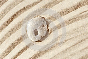 Minimal background with one stone with hole on fine sand with wave ripple. Natural happy stone light ivory color. Symbol