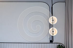 Minimal bedroom corner with circular wall lamp installed on the wall with beige wallcovering in natural light setting scene / photo