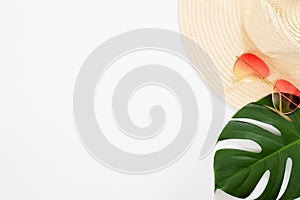 Minimal composition with beach straw hat, sunglasses and tropical Monstera palm leaf on white background. Flat lay, top view still