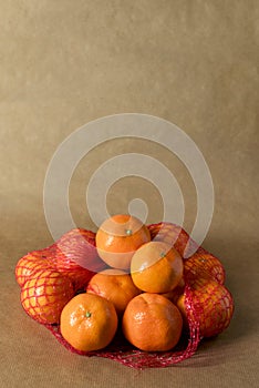 Minimal composition - A net of clementines on brown paper