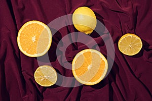 Minimal concept of orange slice and lemon on a beautiful dark red silk or saten background. Summer fresh fruit idea. photo