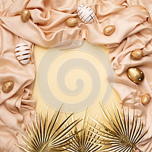 Minimal concept palm leaves with a golden easter eggs on a silk or saten fabric against pastel background with copy space