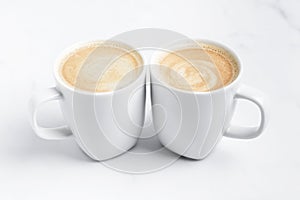 Minimal desk top with two white cups of coffee on marble table. Close-up.