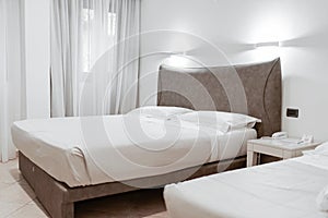 Minimal double bed with white mattress in luxury hotel bedroom. Comfortable bed