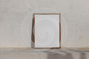 Minimal empty vertical wooden frame picture mockup against white old textured white wall in sunlight. A4, A3, A2 poster