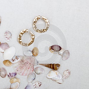 Minimal fashion composition with golden earrings in seashell on table. Flat lay, top view a jewelry concept on mosaic