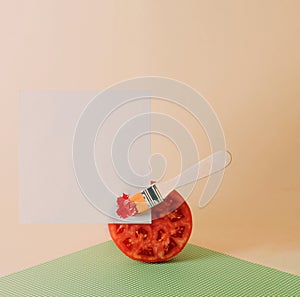 Minimal food concept with paint brush, tomato and copy space against pastel baige background