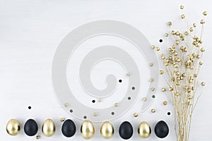 Minimal gold eggs easter concept. Stylish easter golden and black eggs with dried golden flax linum bunch on white