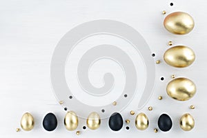 Minimal gold eggs easter concept. Stylish easter golden and black eggs on white wooden background. Flat lay trendy