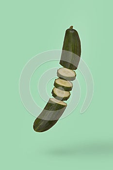 Minimal idea with fresh sliced cucumber floating in air isolated on bright green background