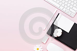 Minimal Office desk table with Keyboard computer, mouse, white pen, cotton flowers, eraser on a pink pastel table with copy space